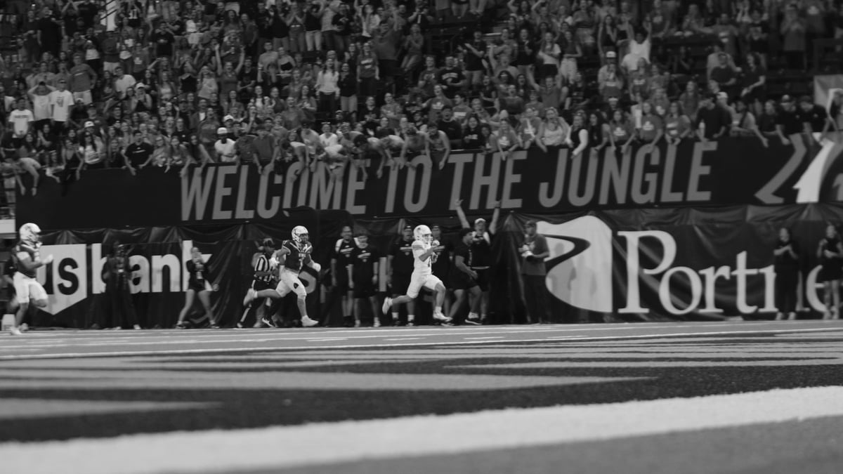 Black and white photo of soccer players on field with Welcome to the Jungle banner and crowd in background